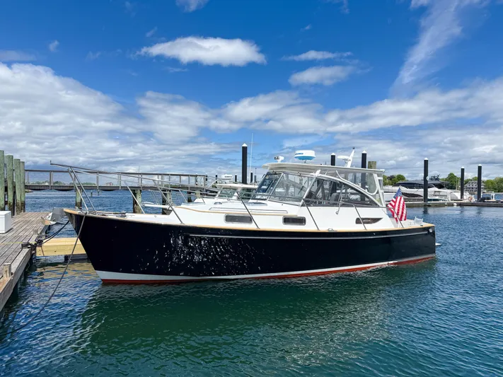 Waypoint Yacht Photos Pics 2002 Legacy 34 Express boat docked in a marina under a blue sky.