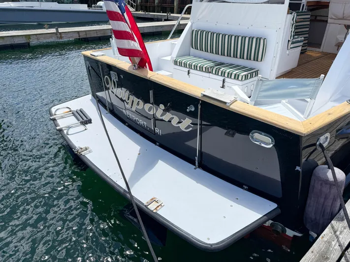 Waypoint Yacht Photos Pics 2002 Legacy 34 Express boat docked, featuring striped seating and American flag.