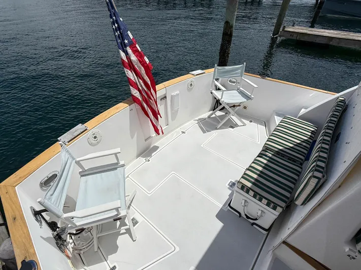 Waypoint Yacht Photos Pics 2002 Legacy 34 Express boat deck with chairs, striped cushion, and American flag.