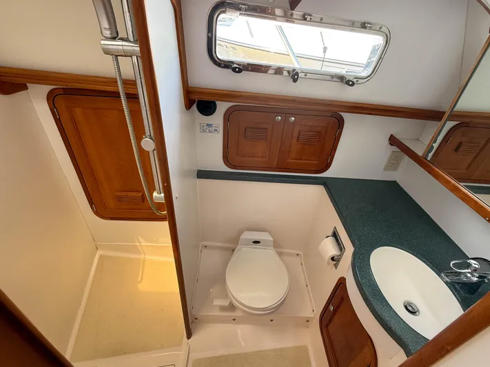 Waypoint Yacht Photos Pics 2002 Legacy 34 Express yacht bathroom with shower, toilet, sink, and wooden cabinetry.