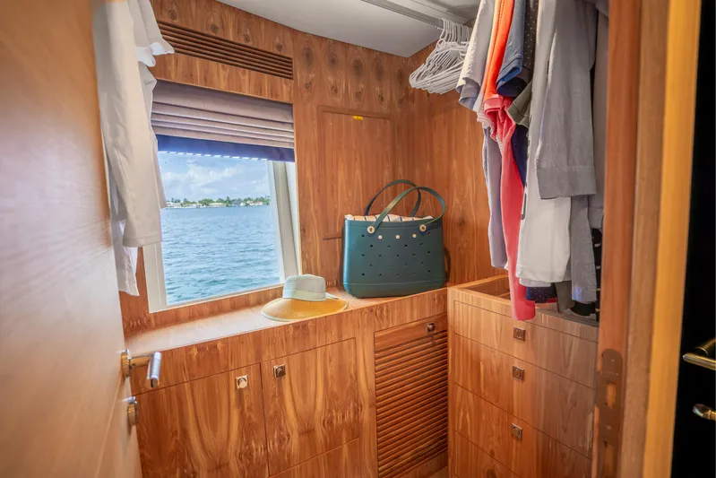 One More Time Yacht Photos Pics Luxurious Horizon FD80 yacht closet with ocean view, wooden cabinetry, and hanging clothes.