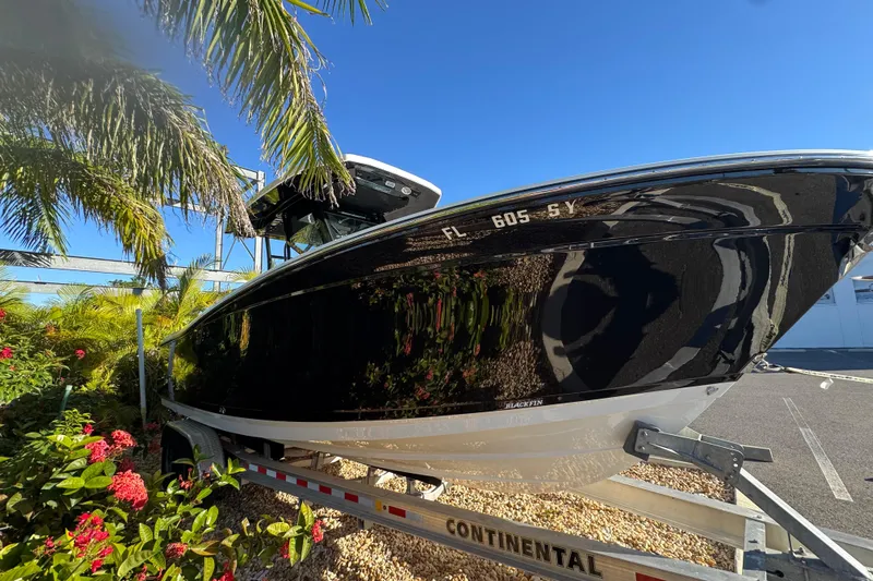  Yacht Photos Pics 2021 Blackfin 272 CC boat on trailer, surrounded by tropical plants.