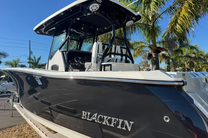  Yacht Photos Pics 2021 Blackfin 272 CC boat with sleek black hull, parked near palm trees.