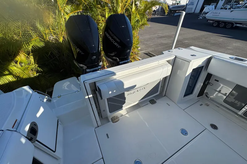  Yacht Photos Pics 2021 Blackfin 272 CC boat with dual Mercury engines, docked near lush greenery.