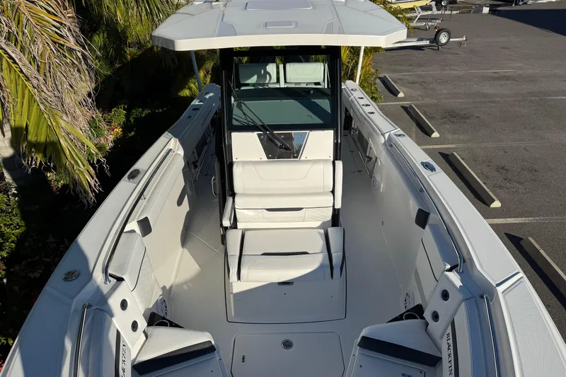  Yacht Photos Pics 2021 Blackfin 272 CC boat interior with seating and helm, parked near palm trees.