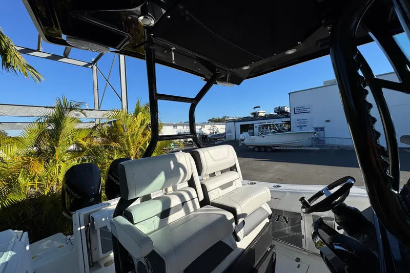  Yacht Photos Pics 2021 Blackfin 272 CC boat interior with dual seats and steering wheel, parked near palm trees.