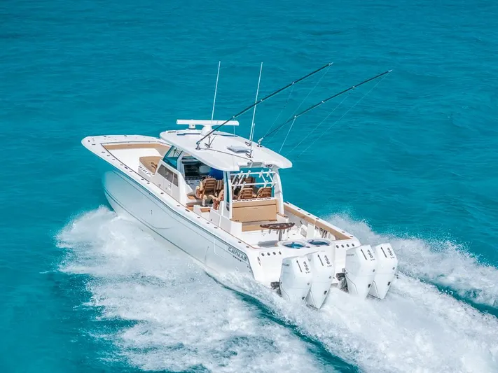  Yacht Photos Pics 2025 Caymas 44 CT boat cruising on clear blue water, equipped with triple outboard engines.