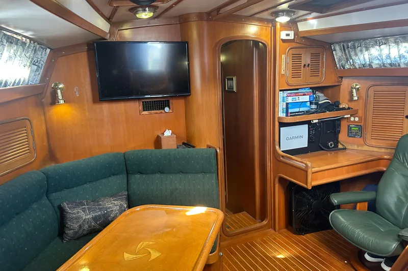  Yacht Photos Pics Interior of 1995 Tayana 48 yacht with wood paneling, green seating, and navigation equipment.
