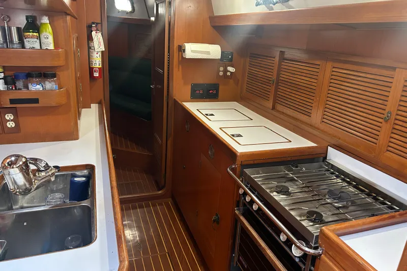  Yacht Photos Pics Interior of 1995 Tayana 48 yacht kitchen with stove, sink, and wooden cabinetry.