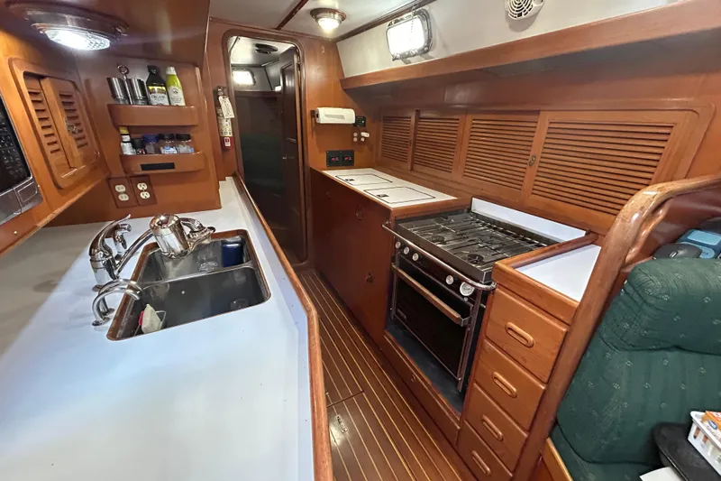  Yacht Photos Pics Interior of 1995 Tayana 48 yacht kitchen with stove, sink, and wooden cabinetry.