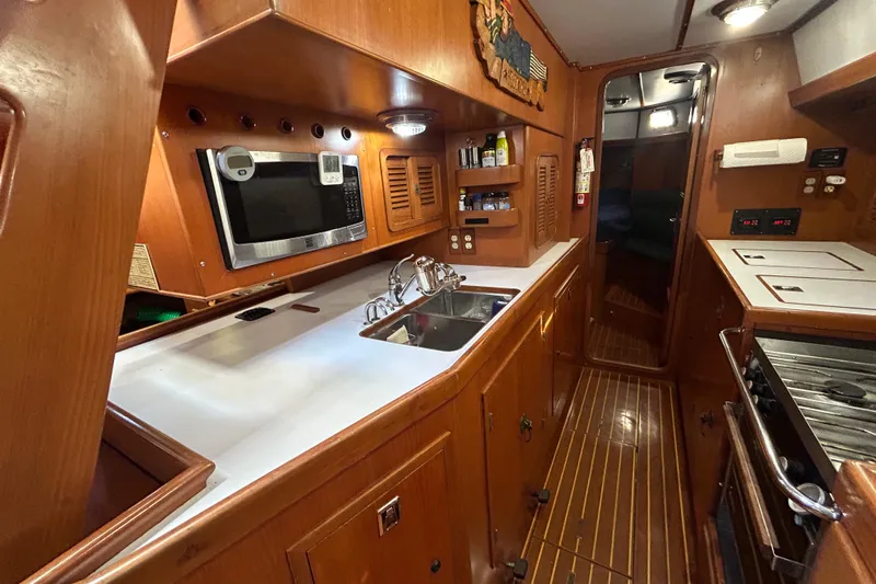  Yacht Photos Pics 1995 Tayana 48 yacht galley with wood cabinetry, microwave, sink, and stove.