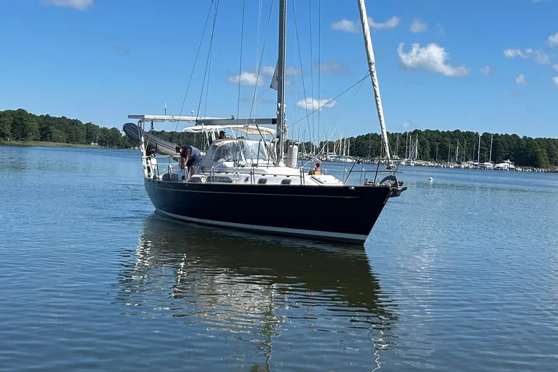  Yacht Photos Pics Sailboat on calm water, 1995 Tayana 48, with clear blue sky and distant marina.
