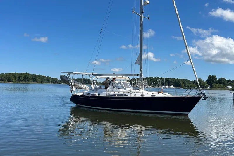  Yacht Photos Pics Sailboat on calm water, 1995 Tayana 48, under clear blue sky.