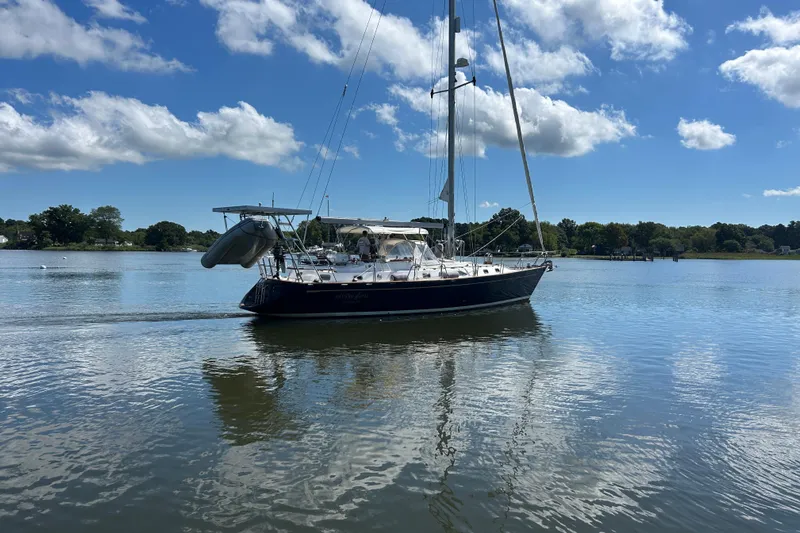  Yacht Photos Pics Sailboat on calm water, 1995 Tayana 48, under a clear blue sky.