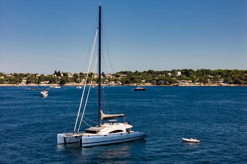 Lyfe At Sea Yacht Photos Pics Sailing yacht "Magic Yachts Custom 2015" on serene blue waters near a coastal town.