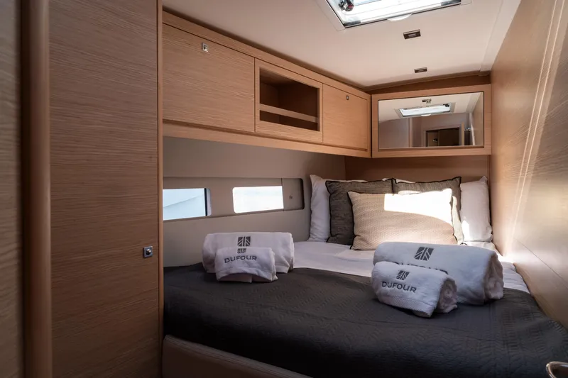  Yacht Photos Pics Luxurious cabin interior of 2024 Dufour 530 yacht with cozy bedding and wooden finishes.