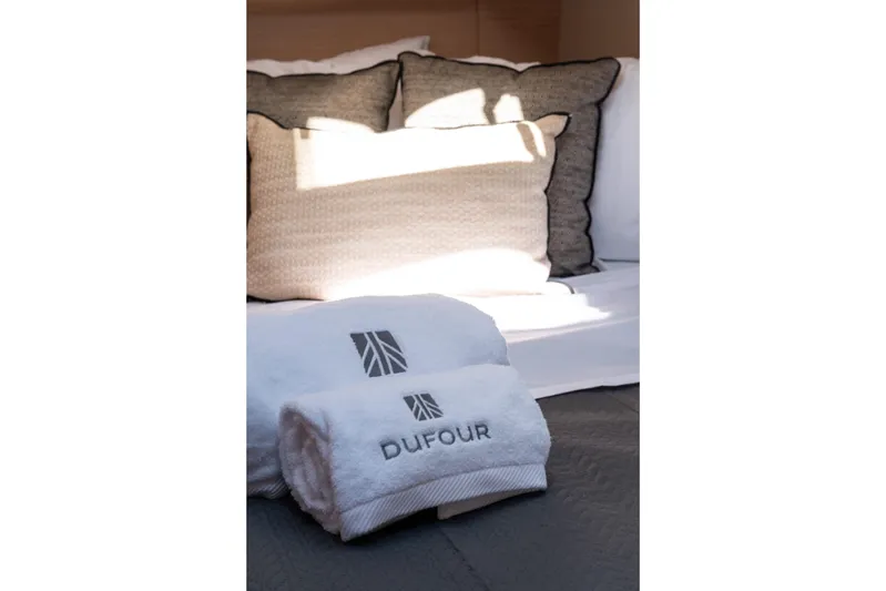  Yacht Photos Pics Luxurious bedding with Dufour-branded towels on a 2024 Dufour 530 yacht.