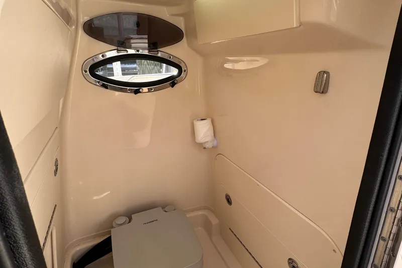  Yacht Photos Pics 2024 Grady-White Fisherman 236 boat interior with compact marine toilet and porthole window.