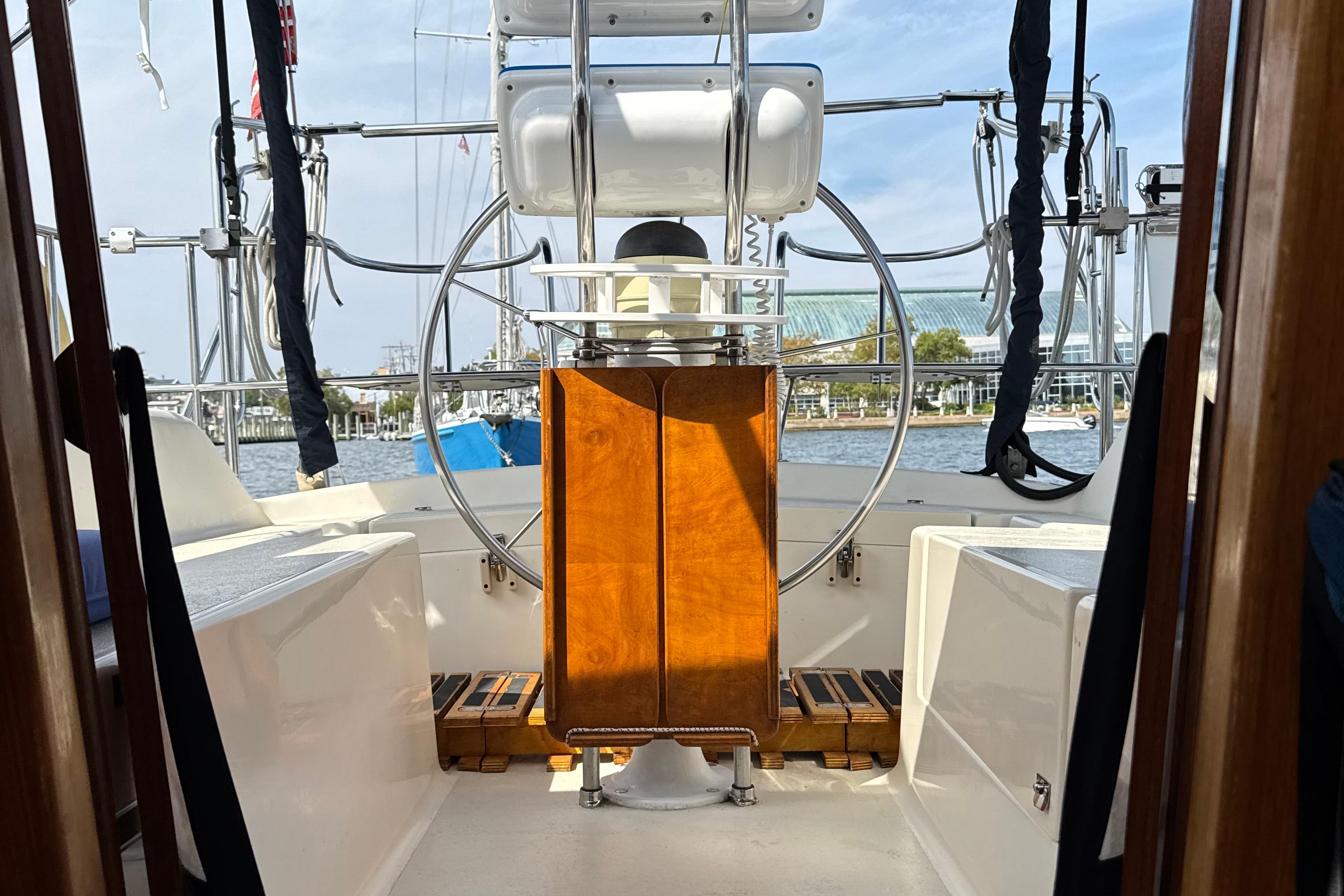 2005 Caliber 40 LRC SE yacht cockpit with steering wheel and wooden panel, docked at marina.