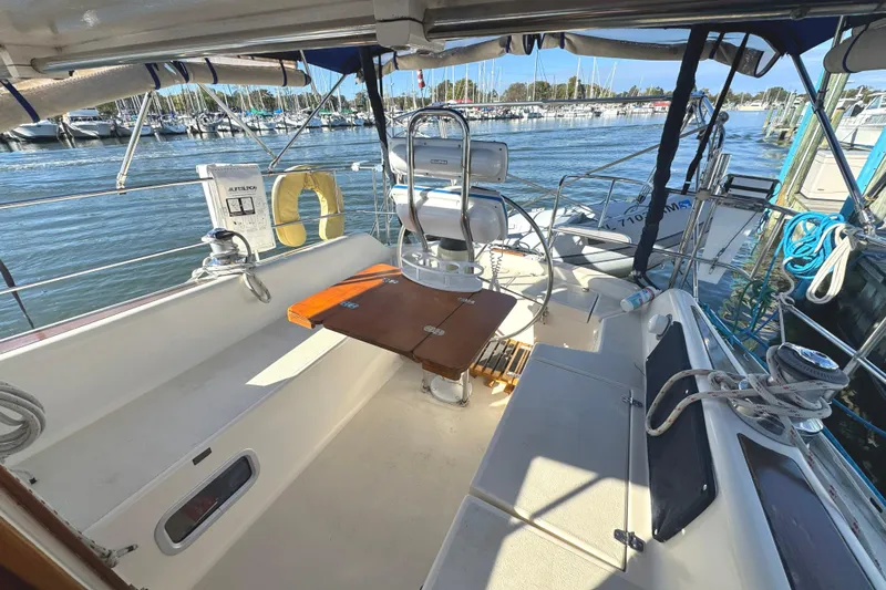 Mer Du Jour Yacht Photos Pics 2005 Caliber 40 LRC SE sailboat cockpit with steering wheel, table, and marina view.