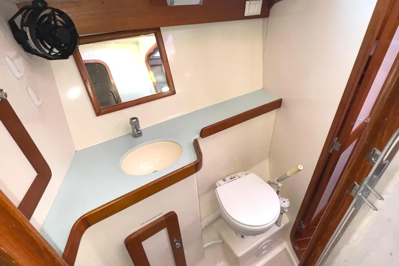 Mer Du Jour Yacht Photos Pics Compact bathroom in 2005 Caliber 40 LRC SE yacht with sink, mirror, and toilet.