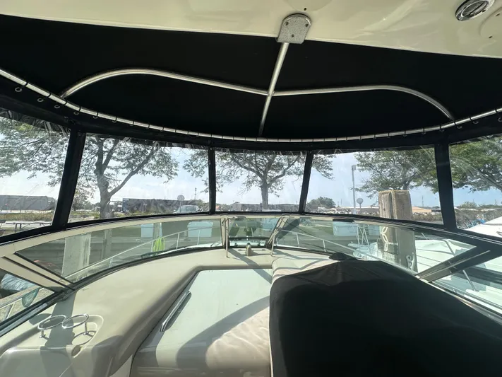  Yacht Photos Pics 2007 Sea Ray 340 Sundancer cockpit with black canopy and clear windows, docked near trees.