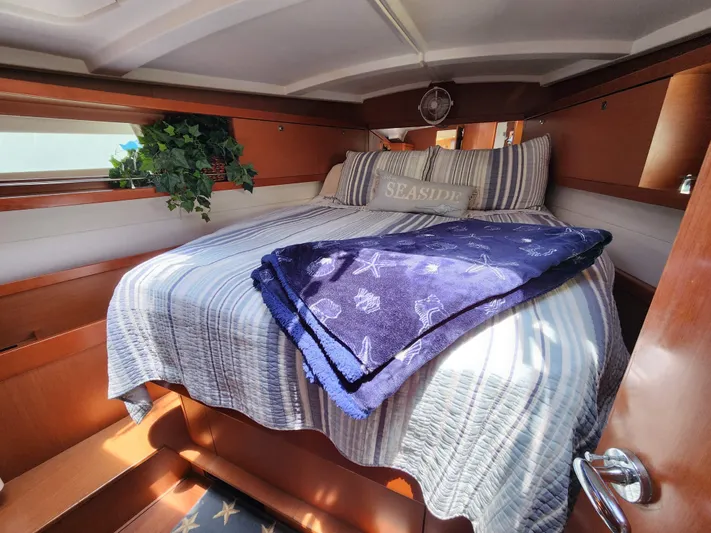 Day One Yacht Photos Pics Cozy cabin interior of 2016 Beneteau Oceanis 45 with striped bedding and nautical decor.