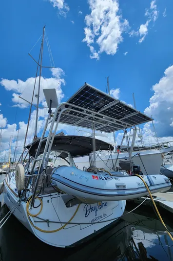 Day One Yacht Photos Pics 2016 Beneteau Oceanis 45 sailboat with solar panels and dinghy, docked under a blue sky.