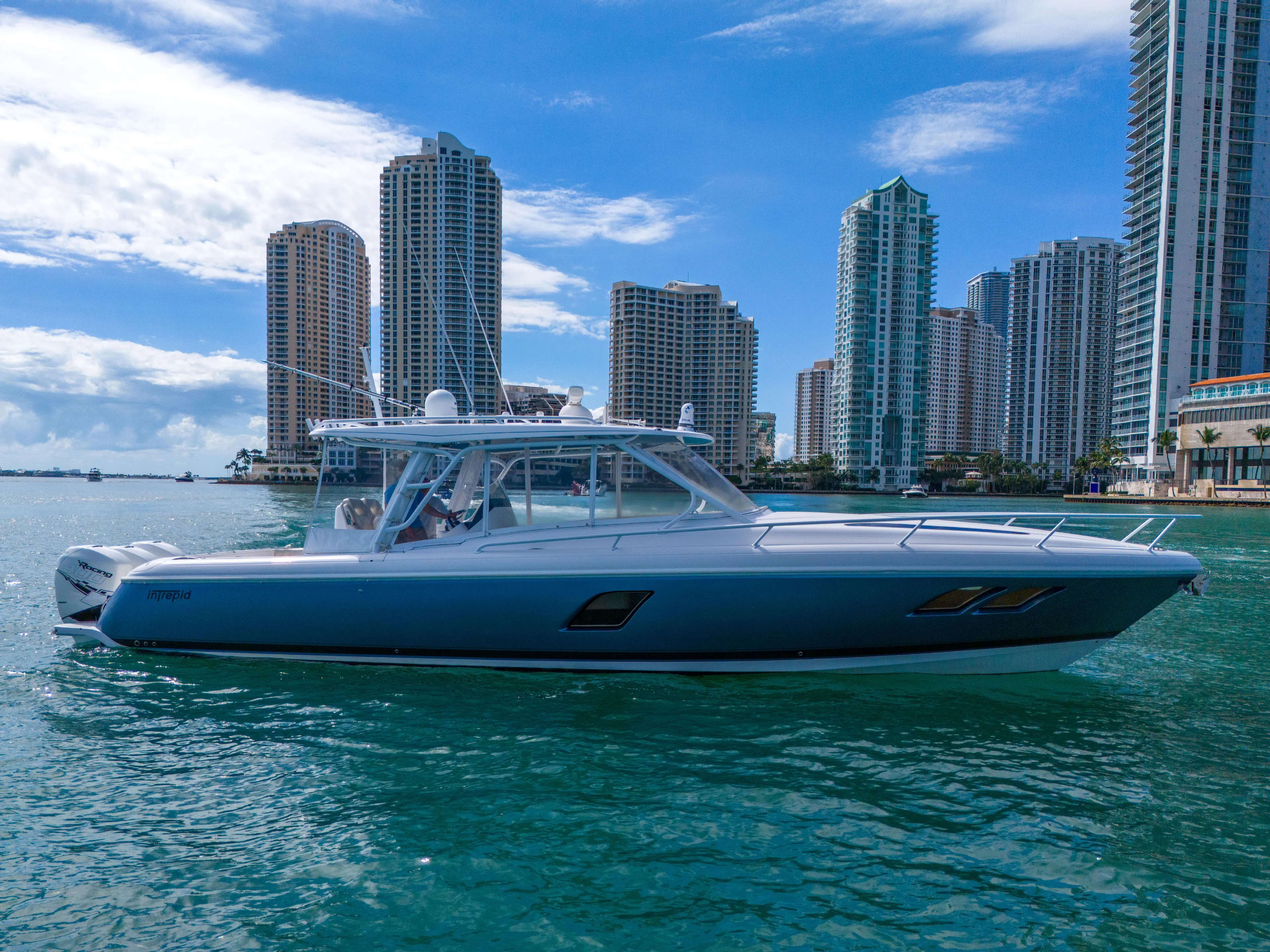  Yacht Photos Pics 2019 Intrepid 407 Cuddy boat cruising near city skyline on a sunny day.