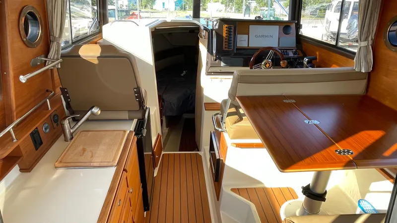  Yacht Photos Pics 2023 Ranger Tugs R-27 interior with wood finishes, kitchenette, and seating area.