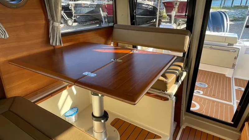  Yacht Photos Pics Interior of 2023 Ranger Tugs R-27, featuring a wooden dining table and cushioned seating.