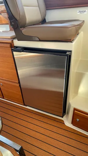  Yacht Photos Pics 2023 Ranger Tugs R-27 interior with stainless steel mini fridge and wooden flooring.