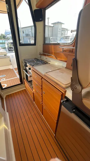  Yacht Photos Pics 2023 Ranger Tugs R-27 interior with wooden cabinetry and compact kitchen area.