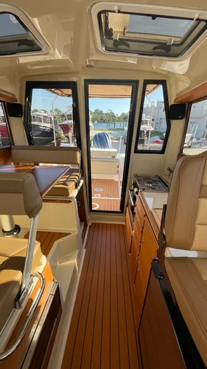  Yacht Photos Pics 2023 Ranger Tugs R-27 interior with wood flooring and seating, showcasing a modern, compact design.
