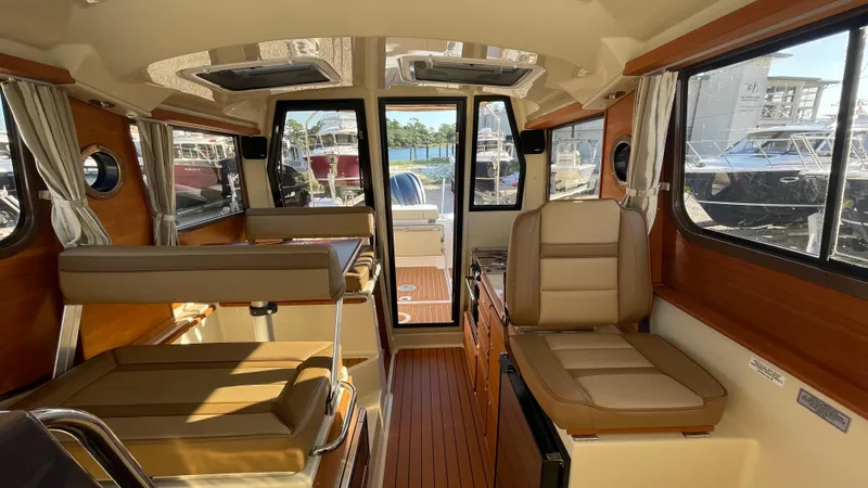  Yacht Photos Pics 2023 Ranger Tugs R-27 interior with seating, wood accents, and large windows.