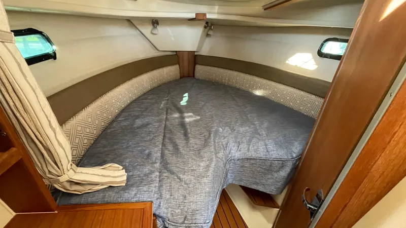  Yacht Photos Pics 2023 Ranger Tugs R-27 cabin interior with cozy bed and wooden accents.