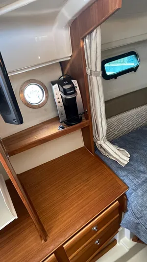  Yacht Photos Pics 2023 Ranger Tugs R-27 cabin interior with wood finish, coffee maker, and porthole window.