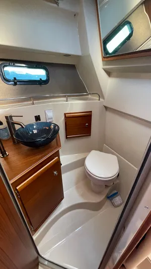  Yacht Photos Pics 2023 Ranger Tugs R-27 boat bathroom with modern sink, toilet, and wooden cabinetry.