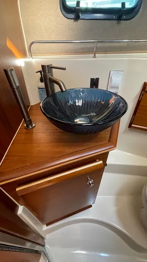  Yacht Photos Pics 2023 Ranger Tugs R-27 bathroom with elegant black vessel sink and wooden cabinetry.