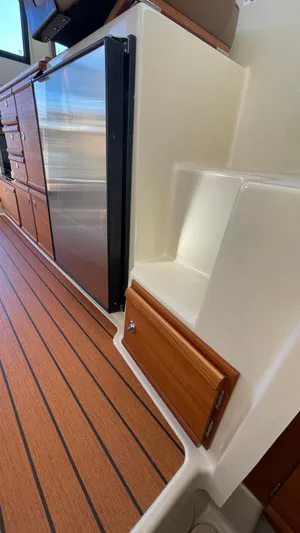  Yacht Photos Pics 2023 Ranger Tugs R-27 interior with wood flooring and compact kitchen area.