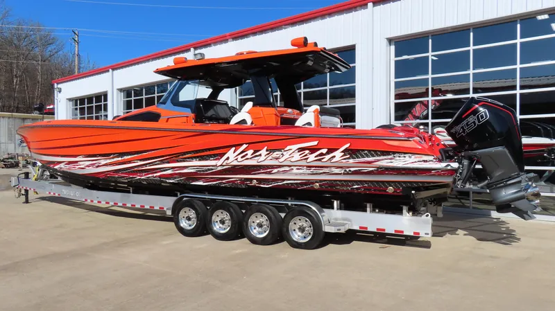  Yacht Photos Pics 2023 Nor-Tech 450 boat in vibrant orange on a trailer outside a garage.
