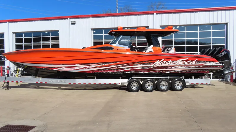  Yacht Photos Pics 2023 Nor-Tech 450 boat in vibrant orange on a trailer outside a garage.