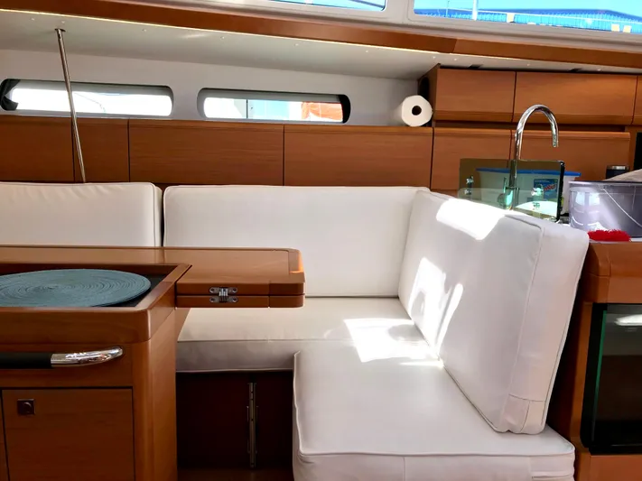  Yacht Photos Pics Interior of 2018 Jeanneau Sun Odyssey 419 yacht with white seating and wooden accents.