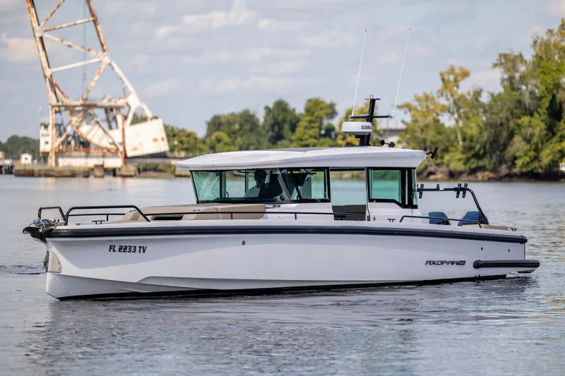  Yacht Photos Pics 2024 Axopar 37 XC boat cruising on a calm river with scenic background.