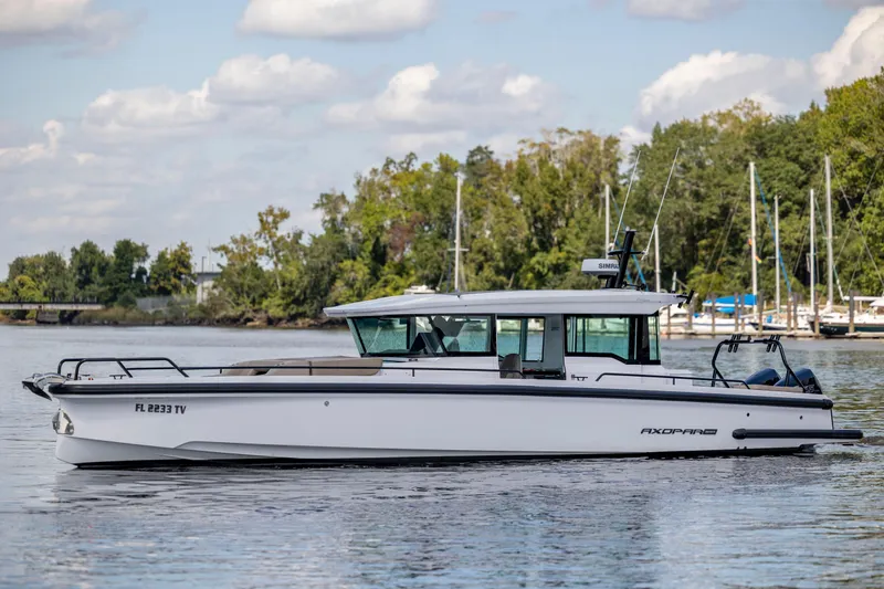  Yacht Photos Pics 2024 Axopar 37 XC boat on calm water with trees and clouds in the background.