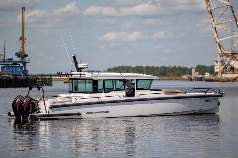  Yacht Photos Pics 2024 Axopar 37 XC boat on calm water near industrial dock.