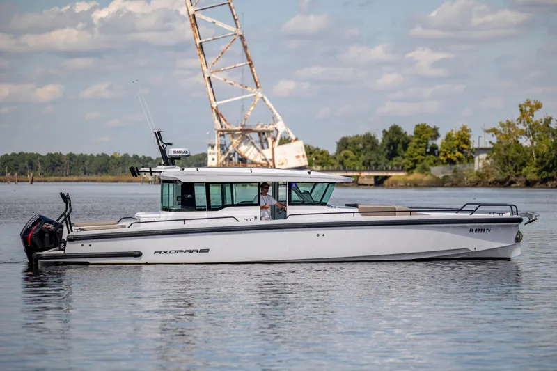  Yacht Photos Pics 2024 Axopar 37 XC boat cruising on a calm river with scenic background.