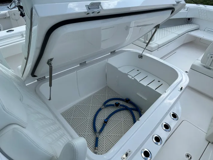  Yacht Photos Pics Open storage compartment on 2021 Invincible 390 Open CC boat with blue hoses inside.