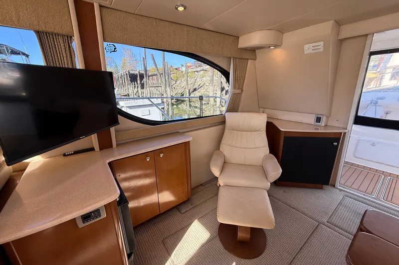 Gra-sea Yacht Photos Pics Interior of 2005 Meridian 381 Sedan yacht with chair, TV, and wooden cabinetry.