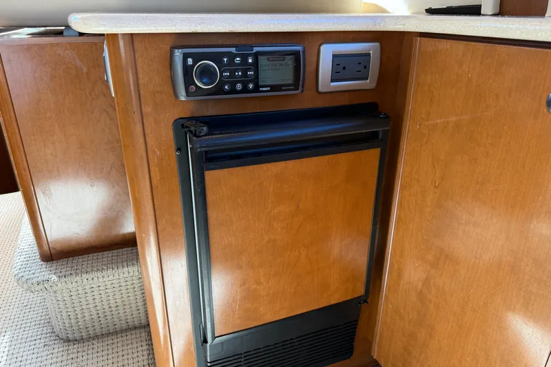 Gra-sea Yacht Photos Pics 2005 Meridian 381 Sedan interior with wooden cabinetry, stereo system, and compact refrigerator.